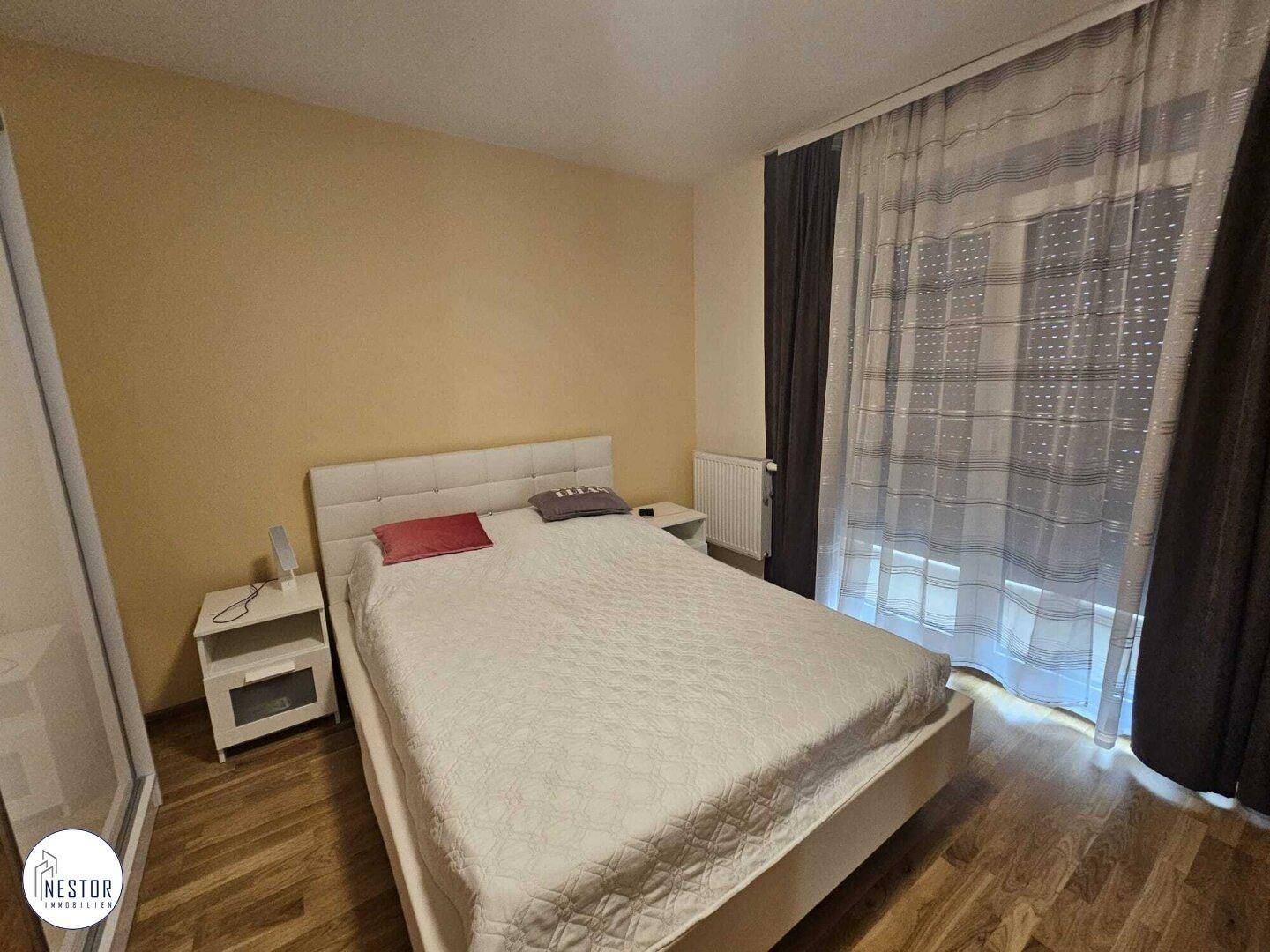 Gemütliches Schlafzimmer mit Doppelbett, Nachttischen und großem Fenster mit Rollos.