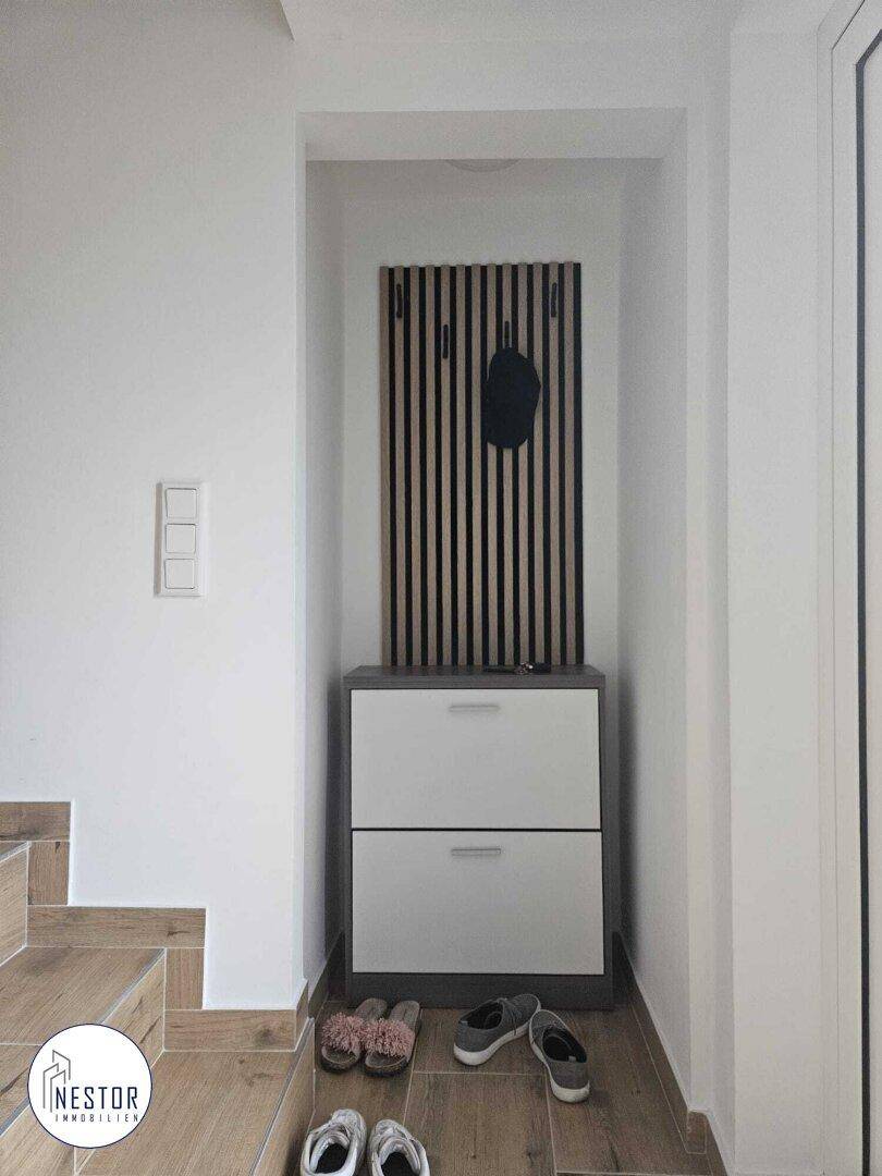 Heller Eingangsbereich mit praktischem Schuhschrank und Garderobe, neben der Treppe.