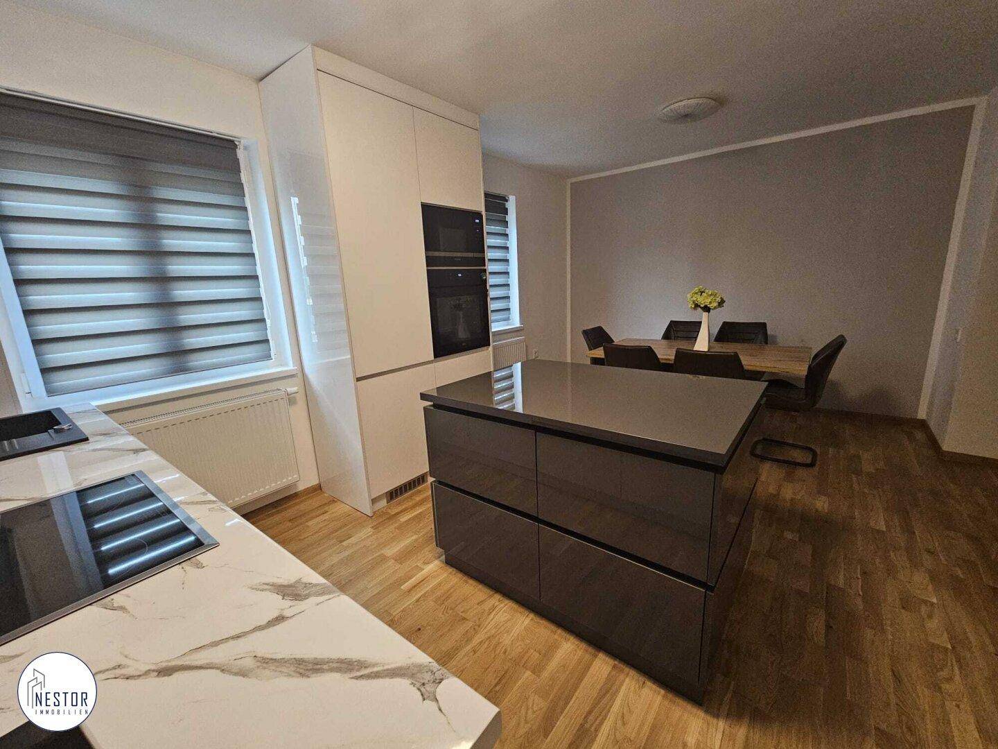 Moderne Küche mit Kochinsel, Induktionskochfeld und Essbereich mit Holztisch.