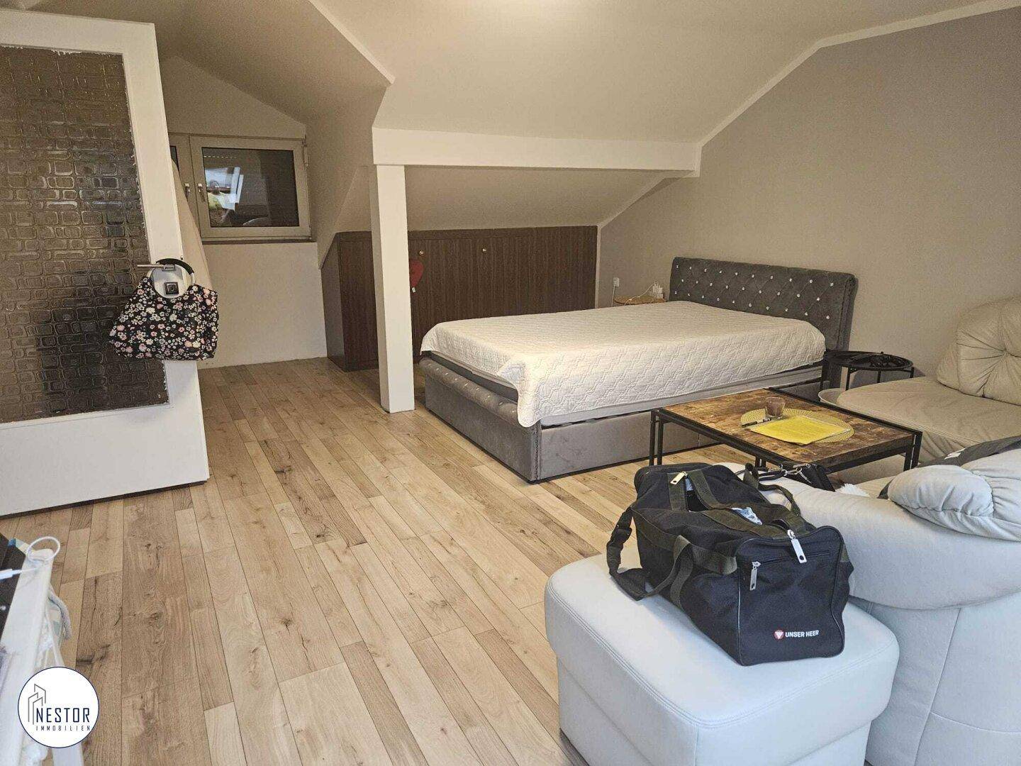 Geräumiges Schlafzimmer im Dachgeschoss mit Holzboden und gemütlicher Einrichtung.