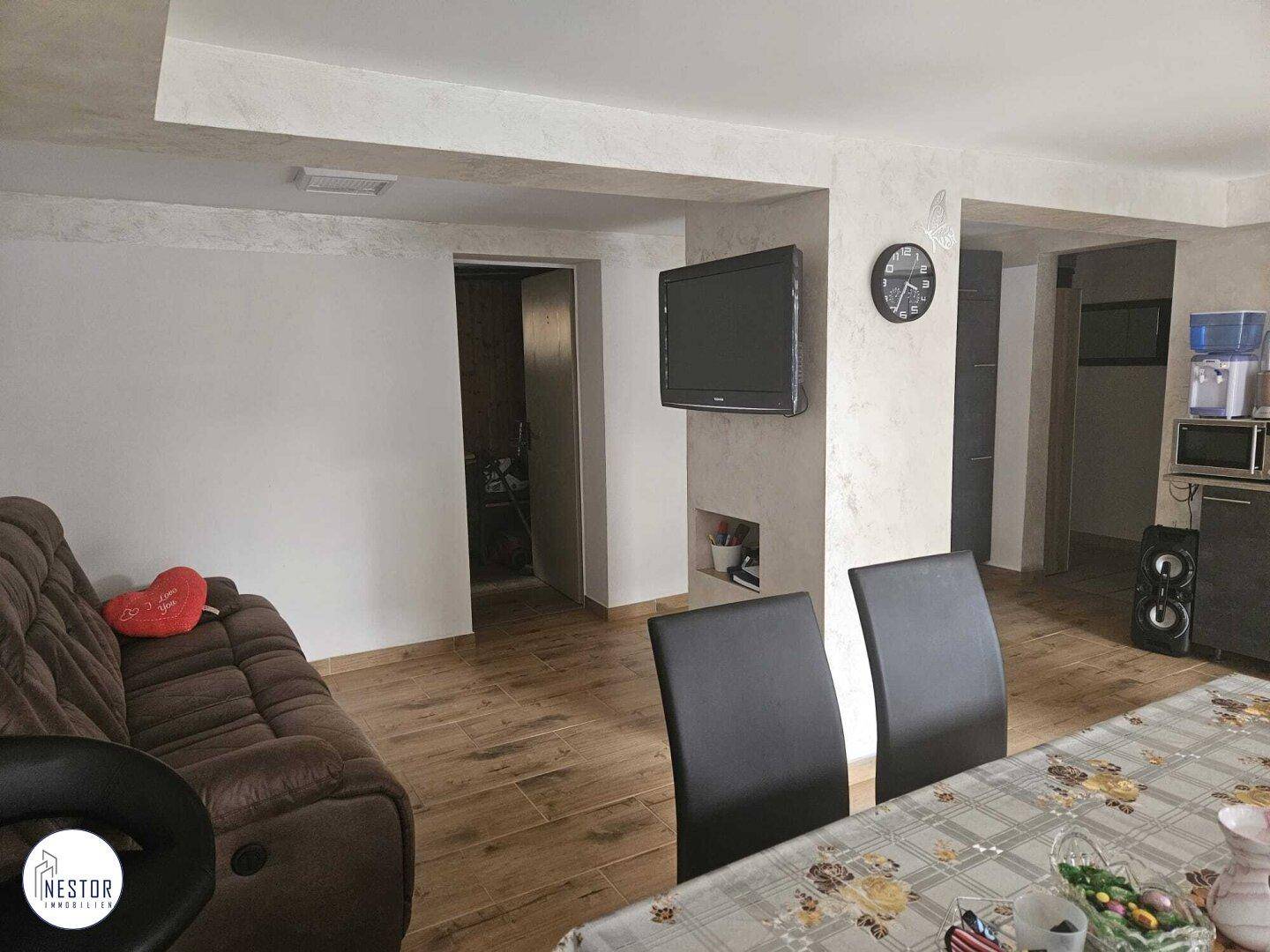 Geräumiger Wohn- und Essbereich mit Sofa, Fernseher und Esstisch.