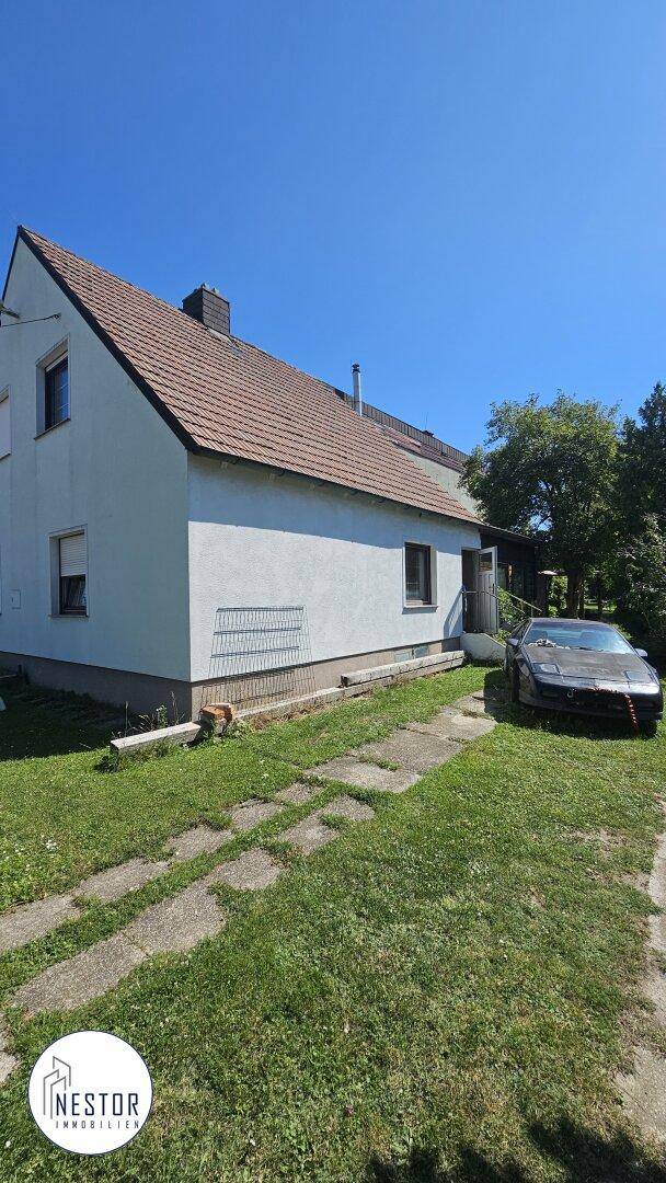 Seitenansicht des Hauses mit Satteldach, Zufahrt und Stellplatz im Freien.