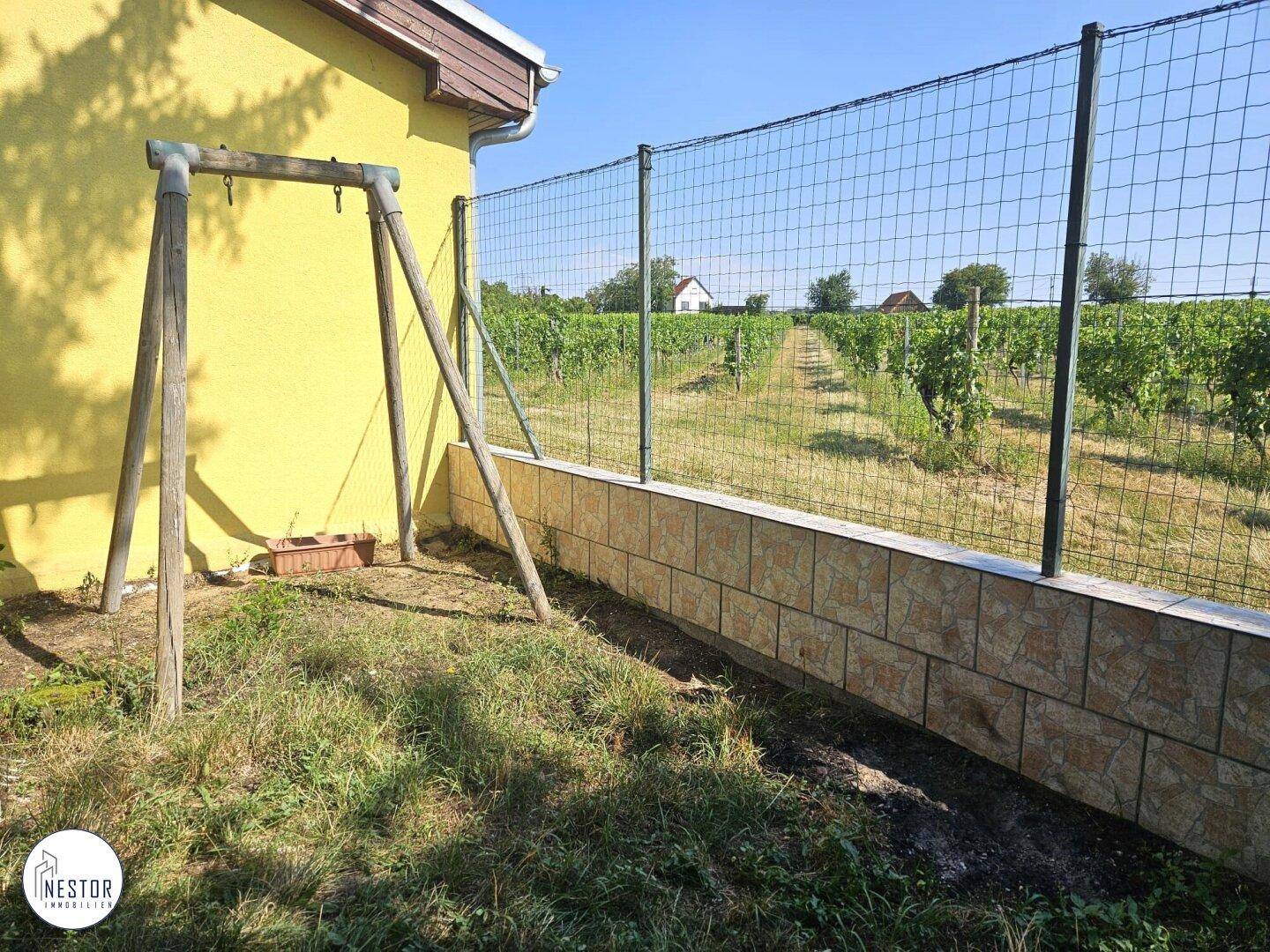 Garten mit Schaukelgestell und freiem Blick auf die umliegenden Weinberge und die Natur.