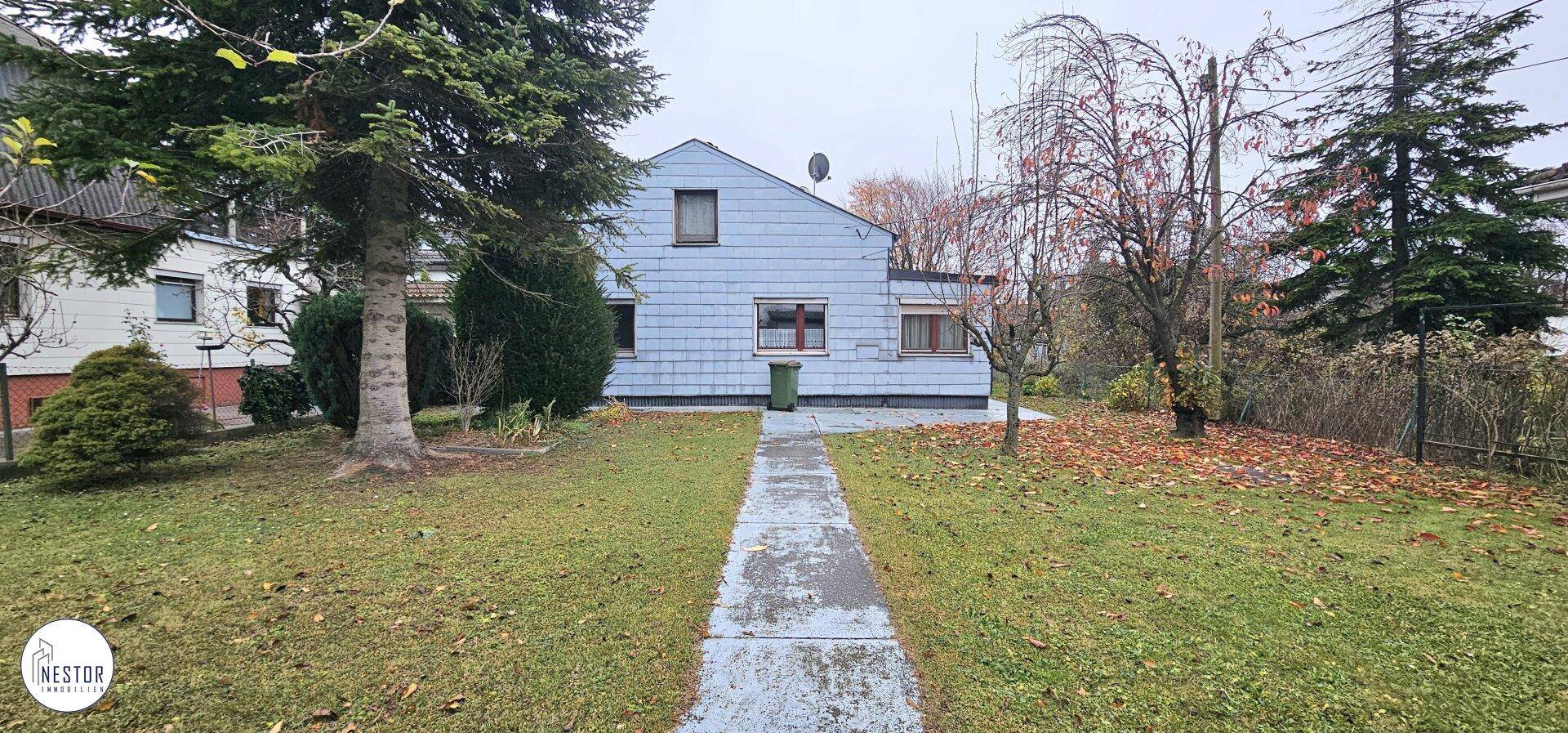 Vorderansicht eines Hauses mit Garten und einem Weg zum Eingangsbereich.