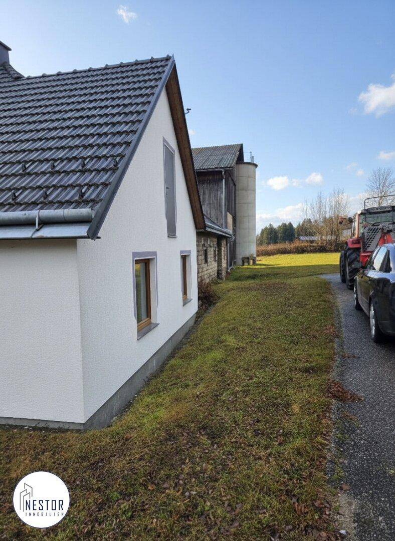 Ansicht des Wohnhauses und der angrenzenden Scheune mit Zufahrt und ländlicher Umgebung.