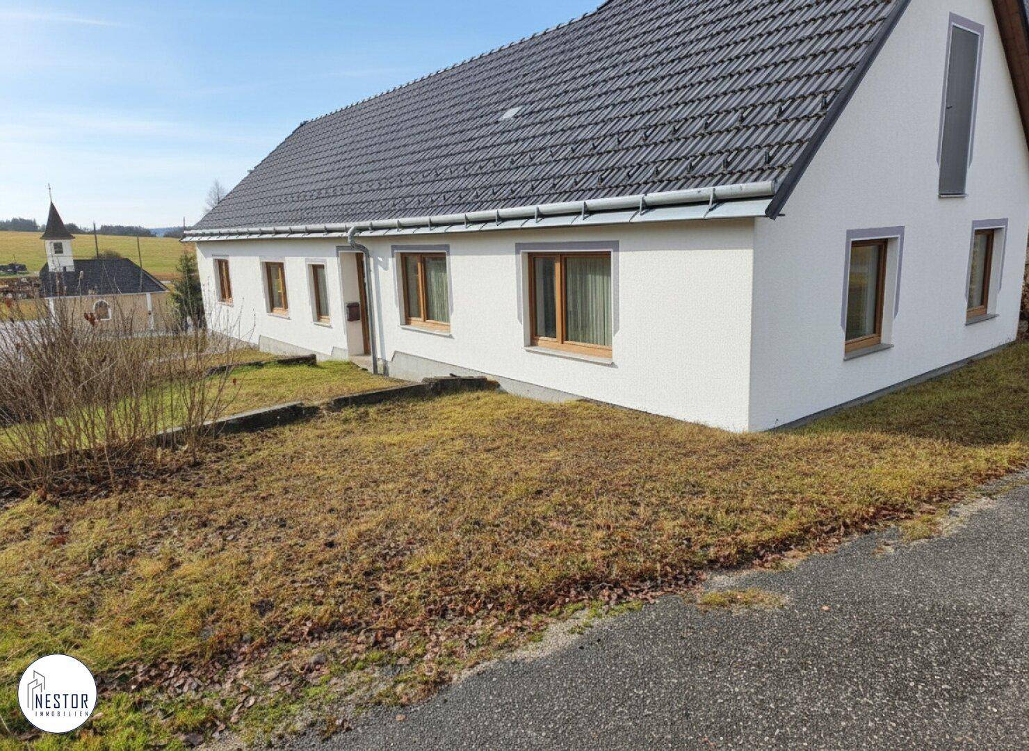 Seitenansicht des Wohnhauses mit gepflegter Fassade und Fenstern in ländlicher Umgebung.