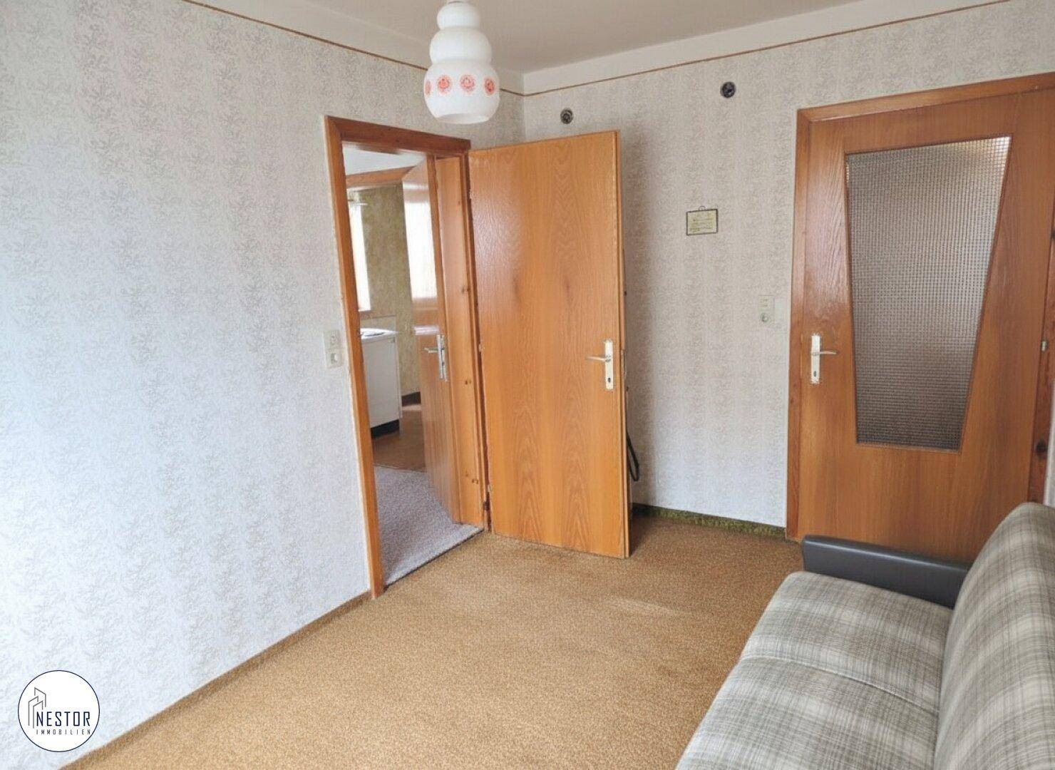 Flur mit Teppichboden und Holztüren, der zu weiteren Räumen führt.