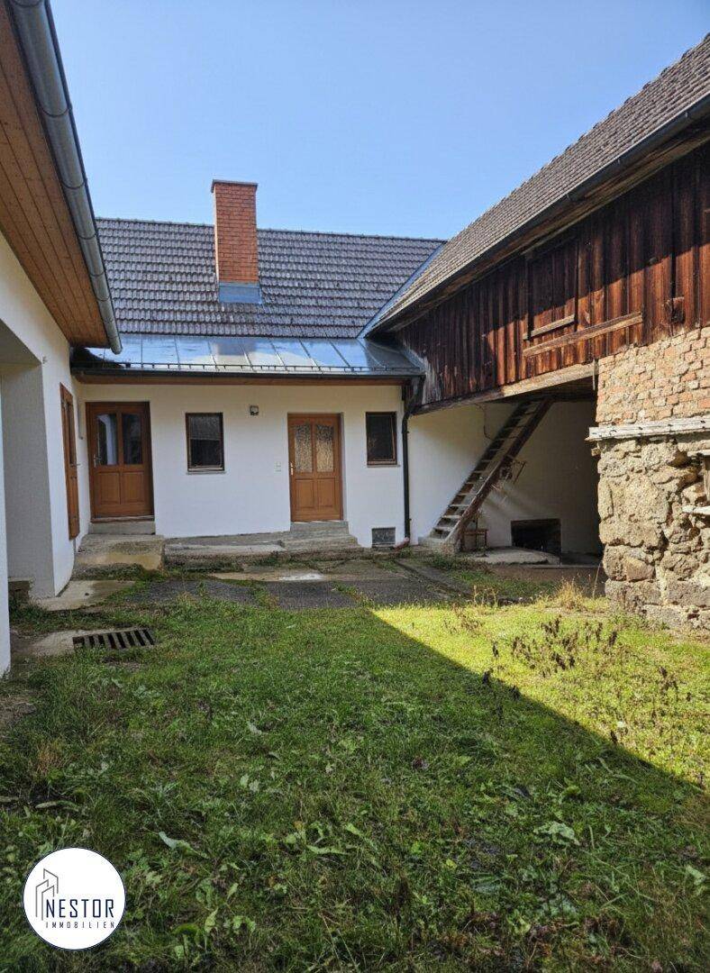 Innenhof des Anwesens mit Grasfläche und Zugang zu verschiedenen Gebäudeteilen.