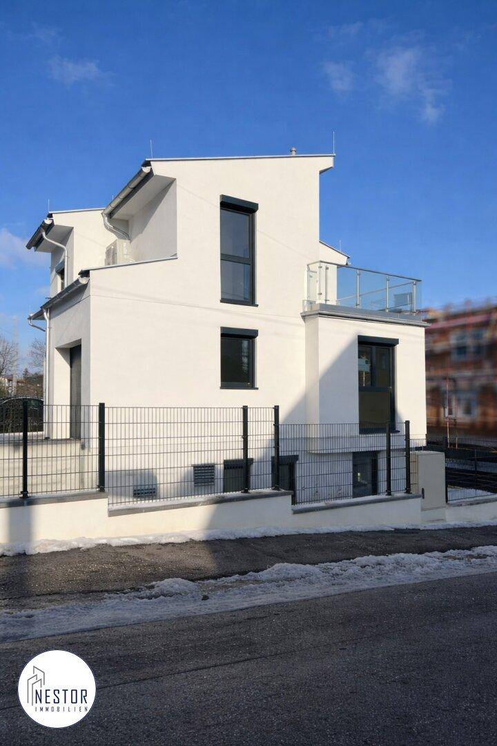 Freistehendes modernes Haus mit weißer Fassade, dunklen Fenstern und Balkon.