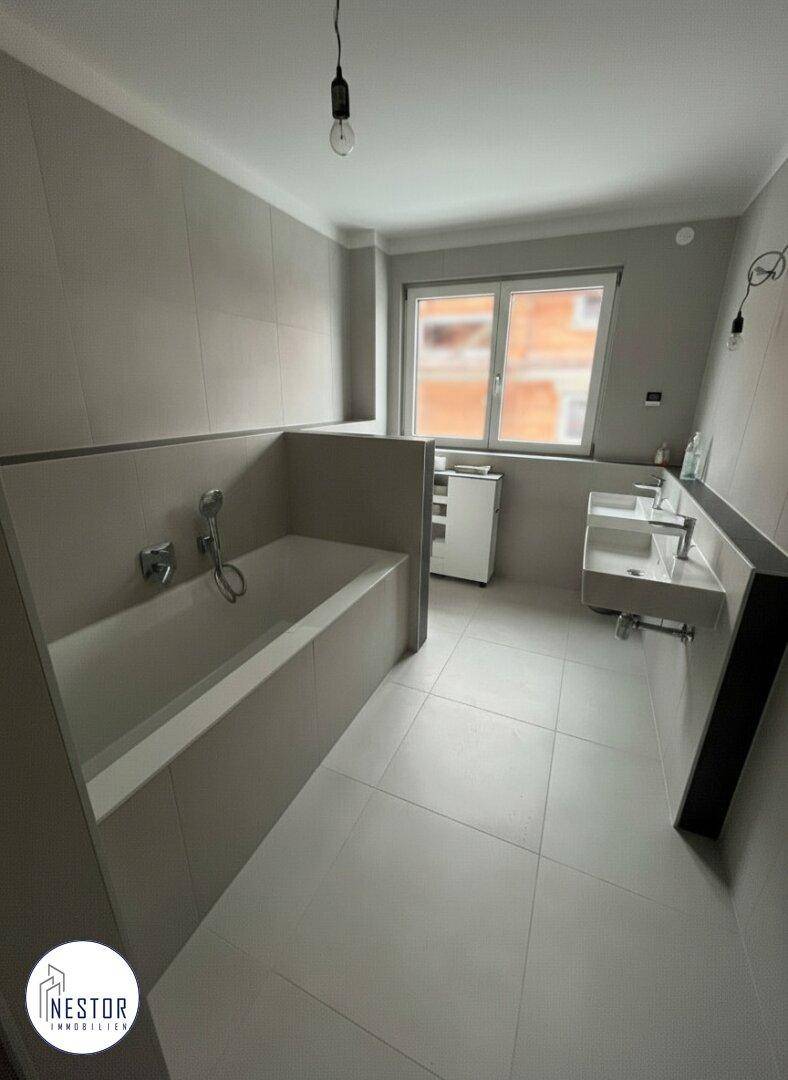 Modernes Badezimmer mit Badewanne, Einzelwaschbecken und grauen Fliesen.