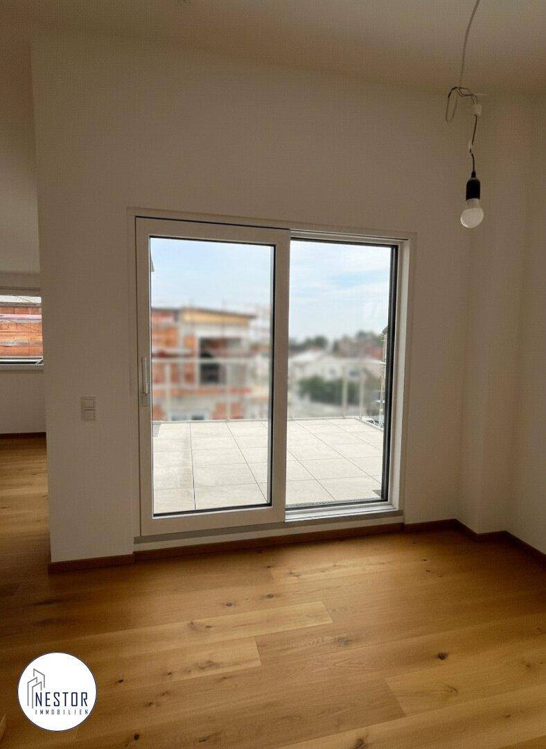 Heller Raum mit Holzboden und großer Schiebetür zur Dachterrasse.