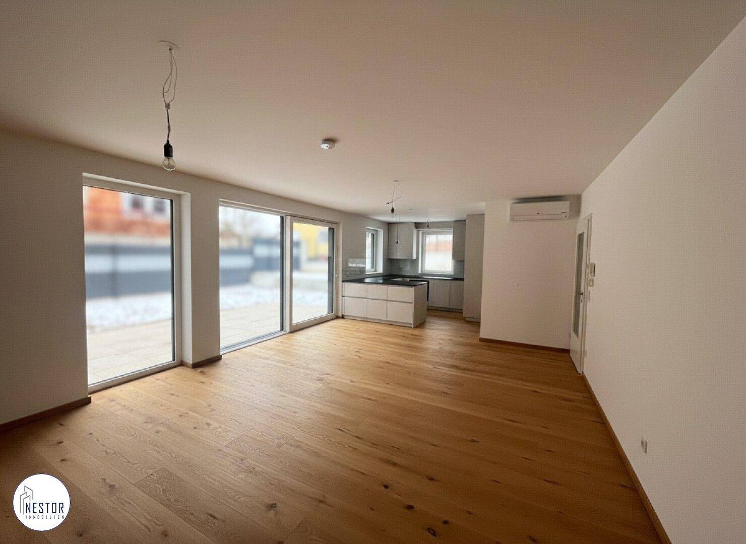 Geräumiger offener Wohnbereich mit Holzboden und Zugang zur Terrasse.