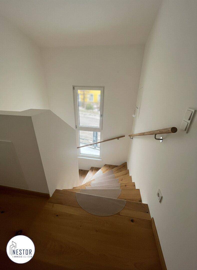 Treppenhaus von oben gesehen mit Holzstufen und Fenster für natürliches Licht.