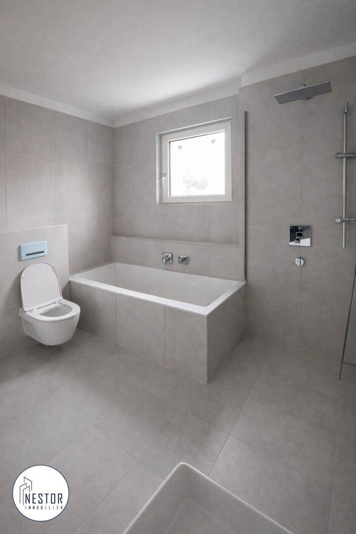 Modernes Badezimmer mit Badewanne, wandhängendem WC, Duschbereich und einem Fenster.