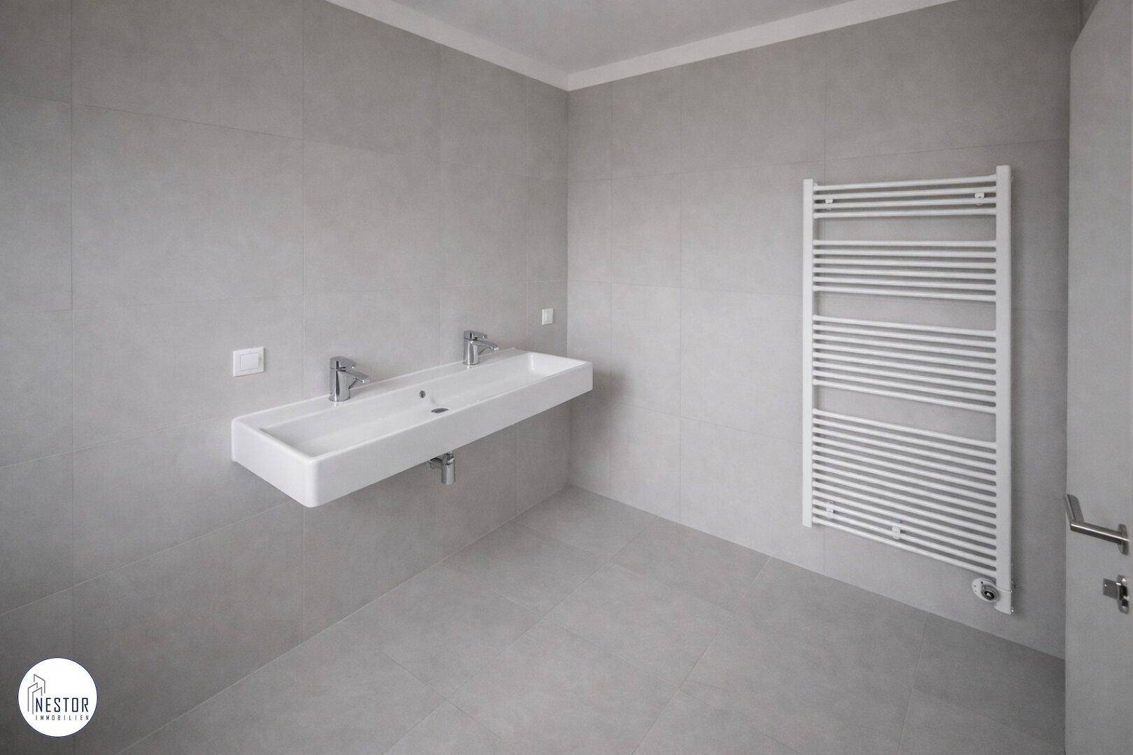 Modernes Badezimmer mit einem breiten Doppelwaschbecken und einem beheizten Handtuchhalter.