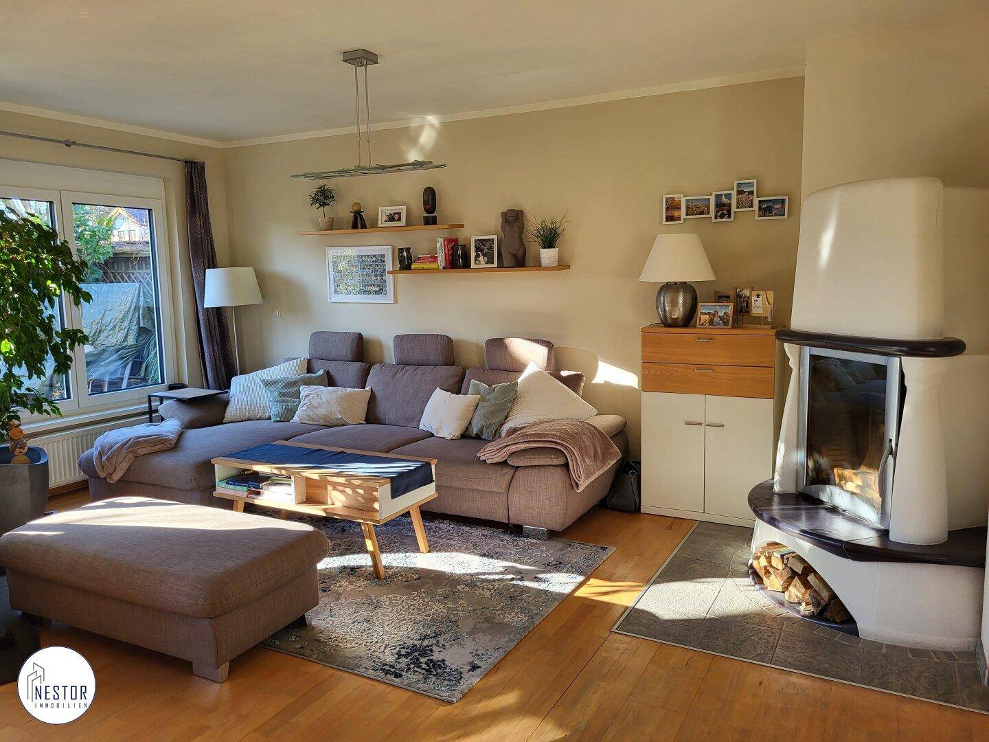 Sonnenlichtdurchflutetes Wohnzimmer mit Kamin und bequemer Sofalandschaft.