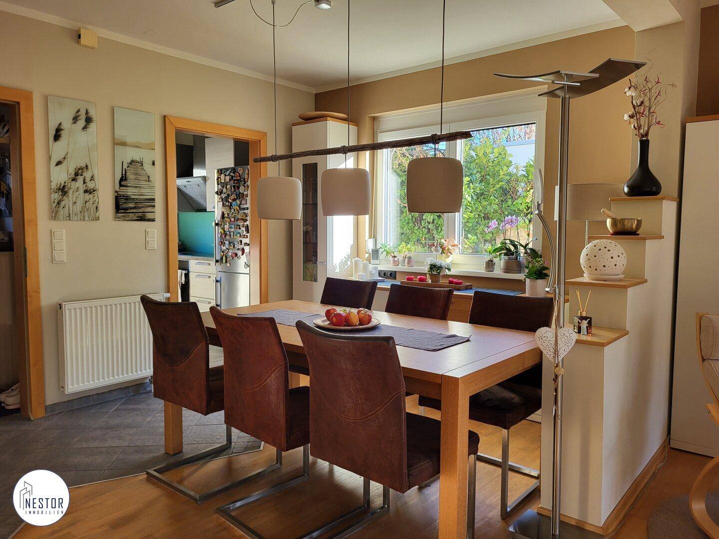 Heller Essbereich mit Holztisch, Fenster und Zugang zur Küche.
