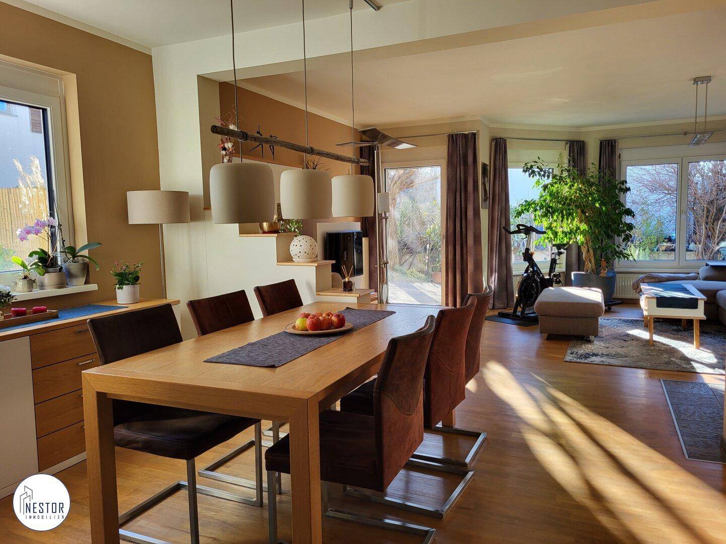 Geräumiger Essbereich mit Holztisch, modernen Hängelampen und Blick ins Wohnzimmer.