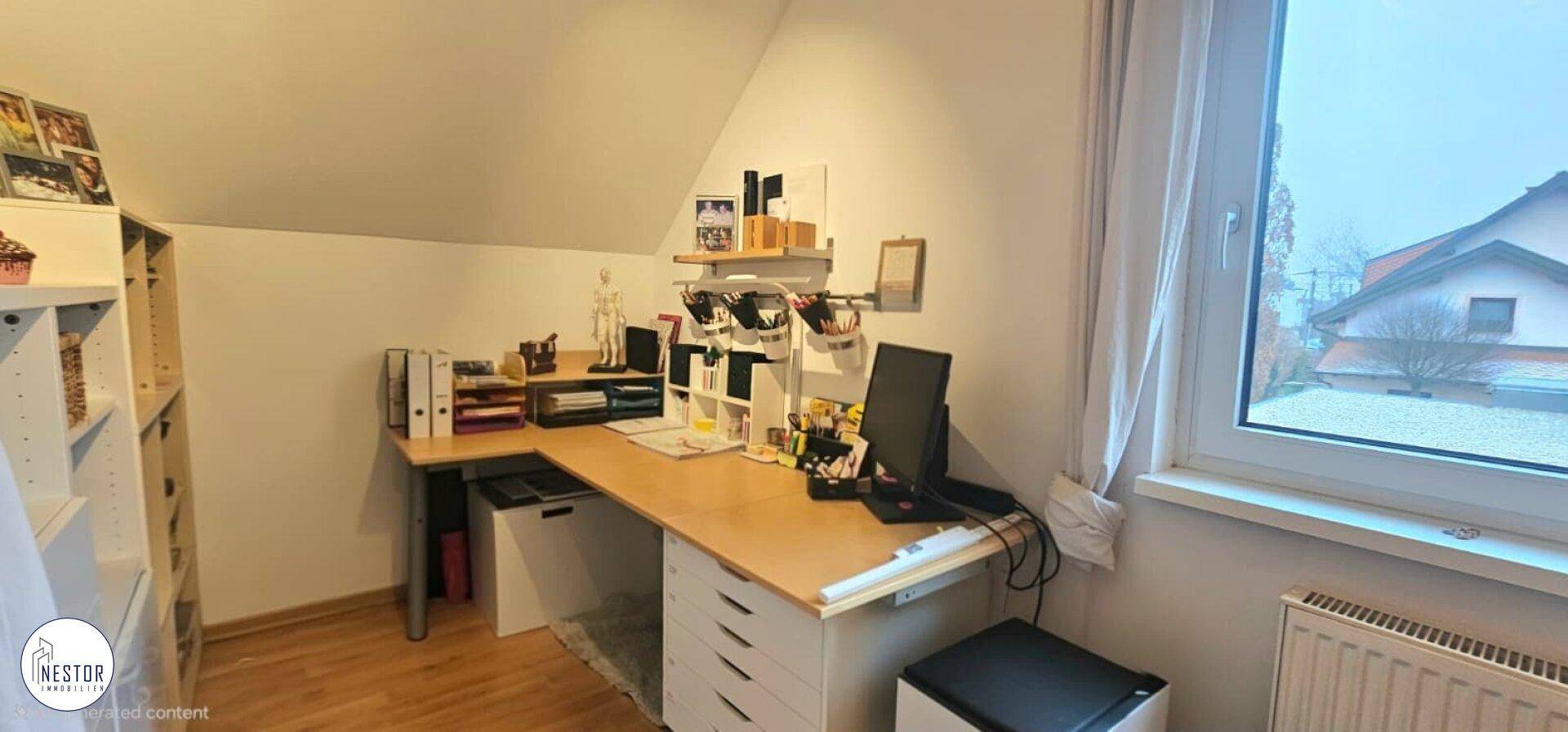 Helles Arbeitszimmer im Dachgeschoss mit Schreibtisch und Fenster.
