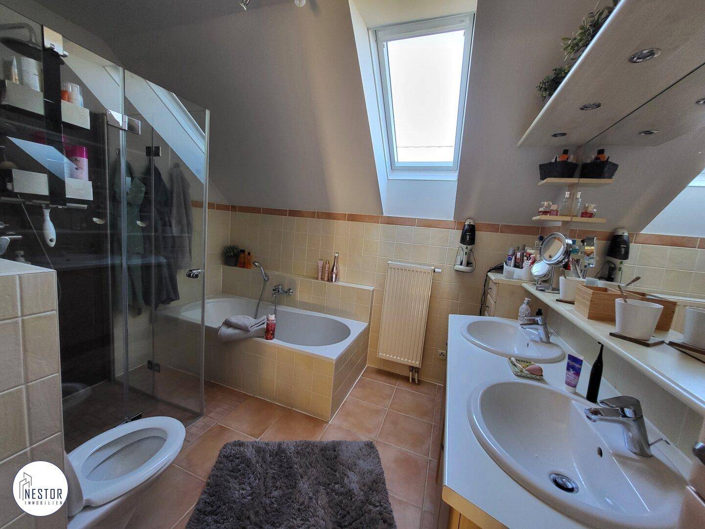 Geräumiges Badezimmer mit Doppelwaschbecken, Badewanne, Dusche und Dachfenster.