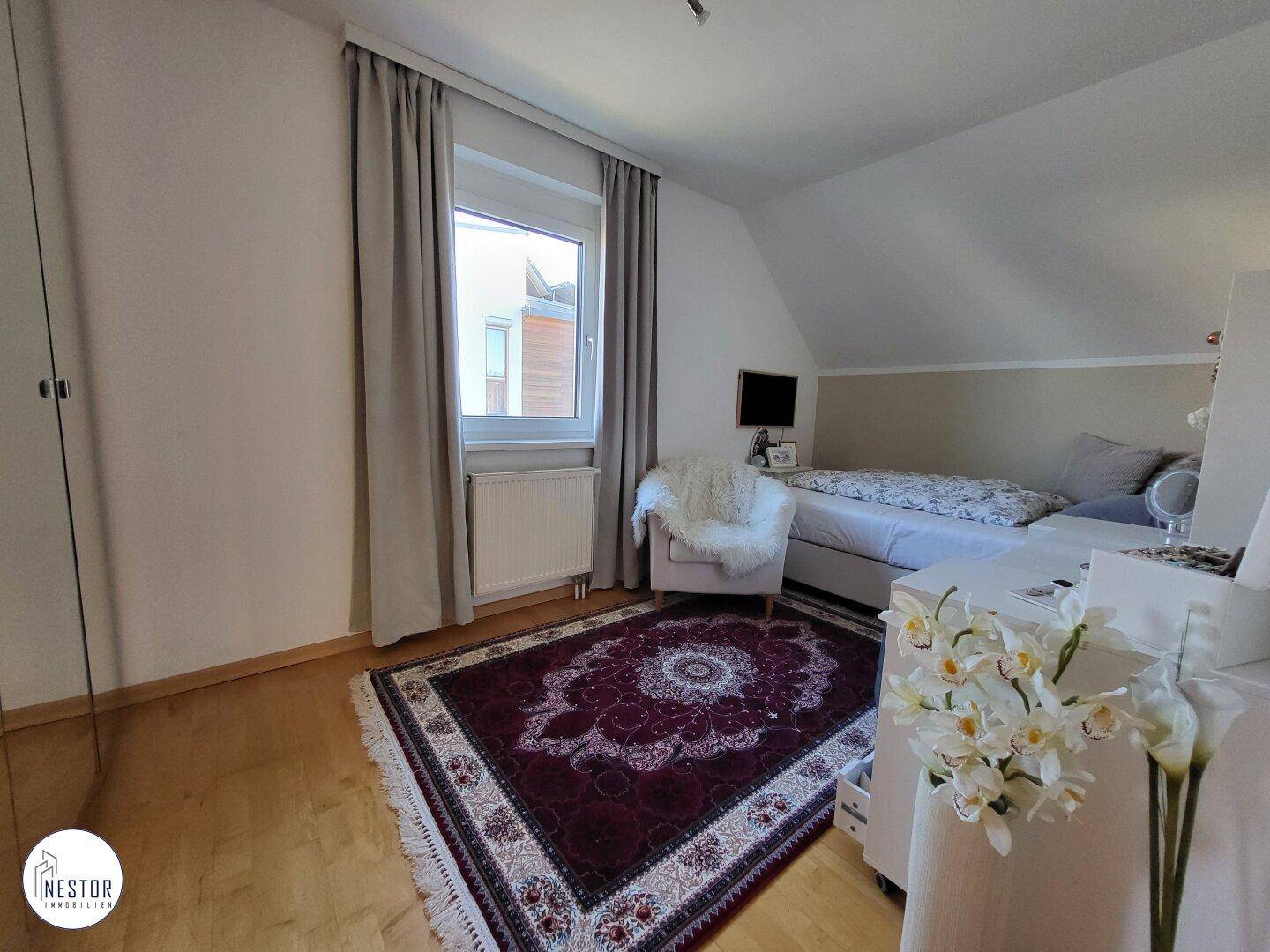 Weiteres Schlafzimmer im Dachgeschoss mit Teppich und Fenster.