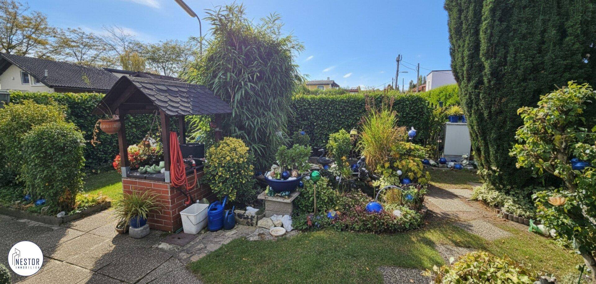 Weitläufiger Garten mit Zierbrunnen, vielfältiger Bepflanzung und einem gepflasterten Gartenweg.