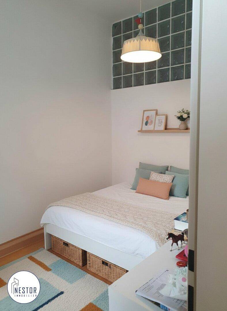 Kleines Schlafzimmer mit Einzelbett, Teppich und dekorativen Elementen an der Wand.