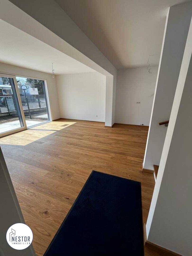 Heller, leerer Wohnbereich mit Holzboden und großen Fenstern, bereit zur individuellen Gestaltung.