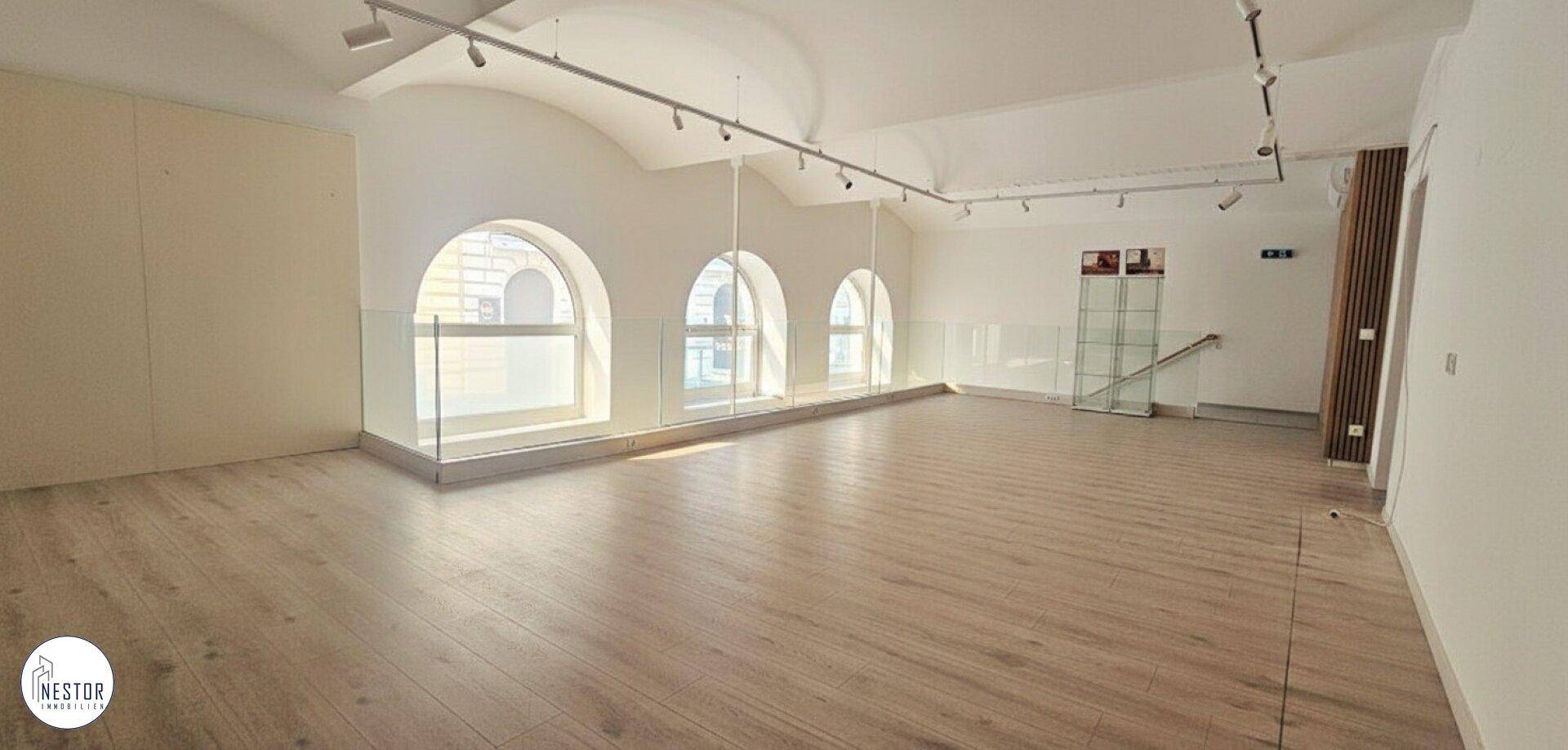 Großer, heller Raum mit gewölbter Decke, Holzboden und großen Rundbogenfenstern mit Glasgeländer.