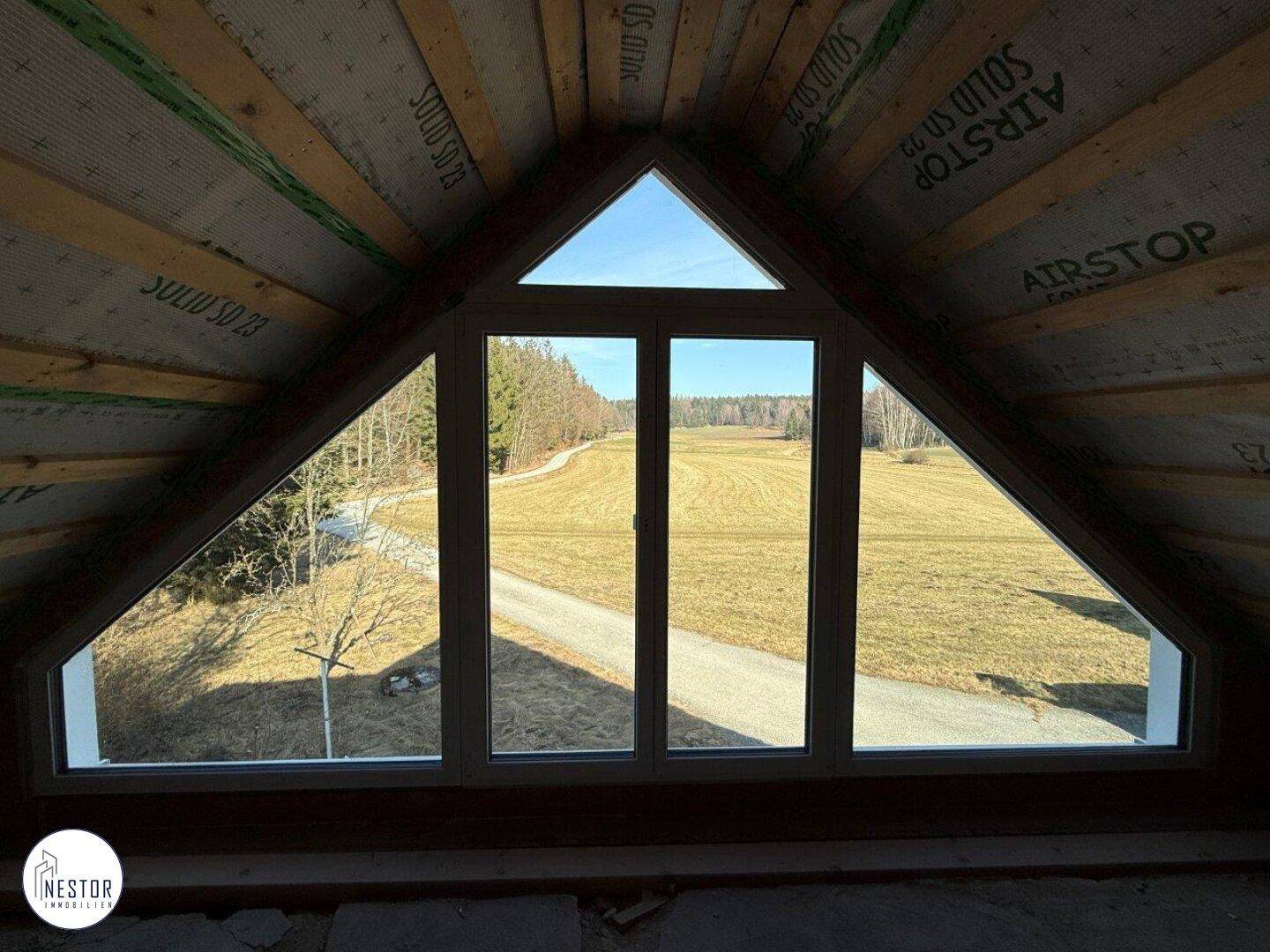 Dachgeschoss mit einzigartigem dreieckigem Fenster, das einen weiten Blick über die ländliche Umgebung bietet.