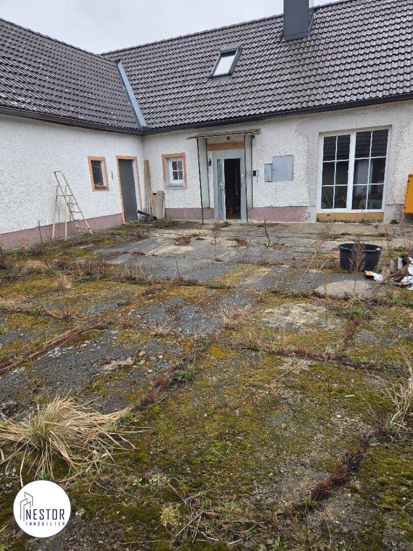 Vorderseite des Hauses mit ungepflegtem Vorplatz und Eingangsbereich, der auf Renovierung wartet.