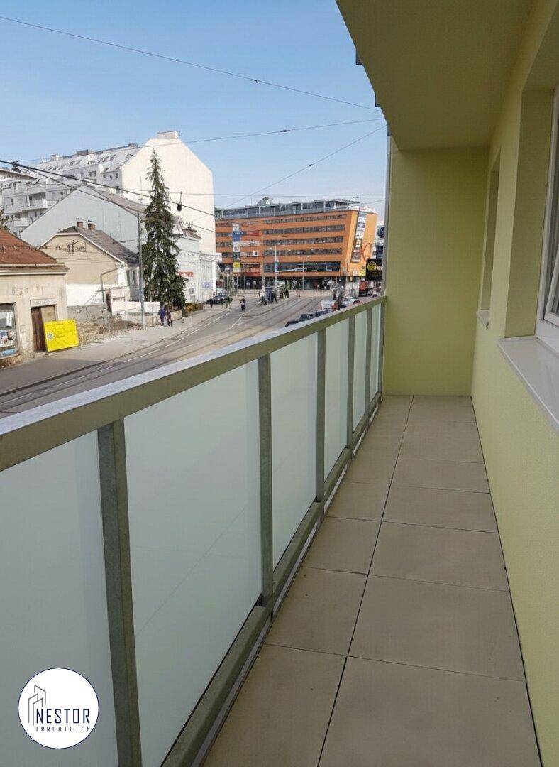 Langer Balkon mit Glasbrüstung und Blick auf die Straße und umliegende Gebäude.