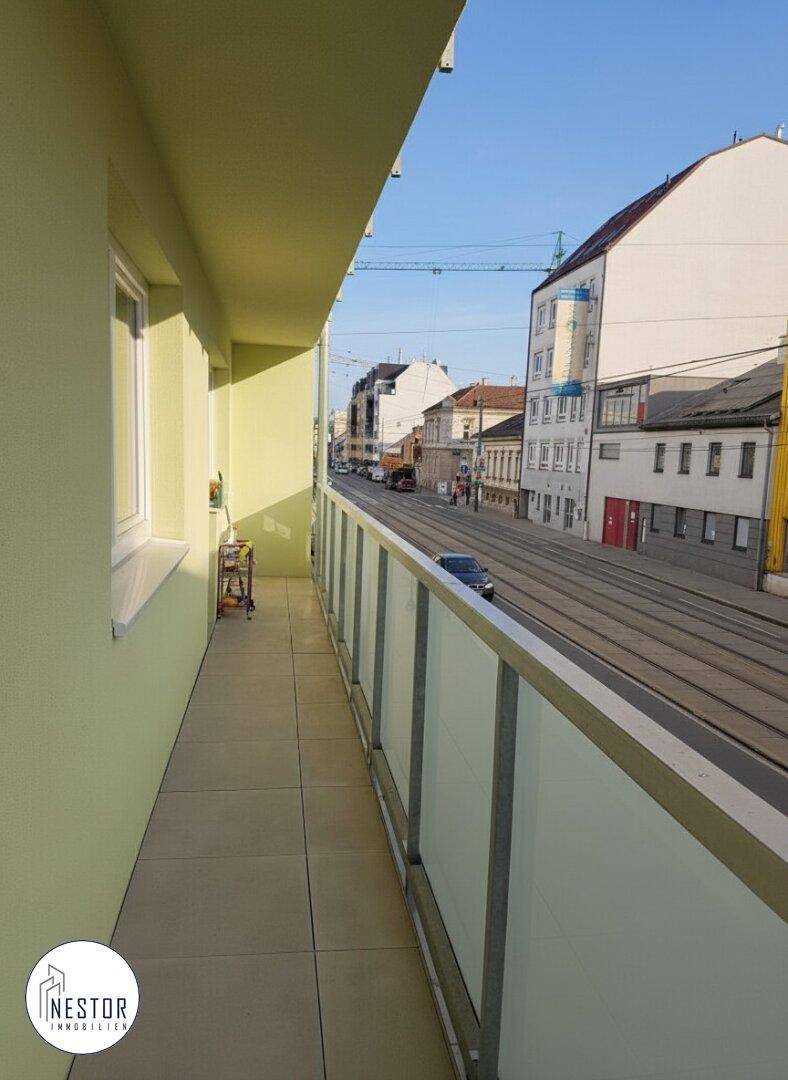 Schmaler Balkon mit Fliesenboden und Blick auf die belebte Straße.
