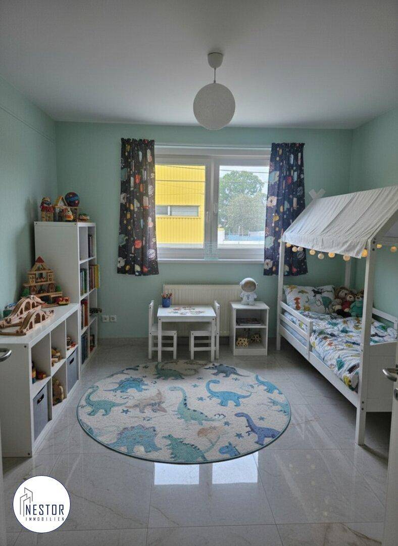 Kinderzimmer mit Spielteppich, Etagenbett und bunten Vorhängen.