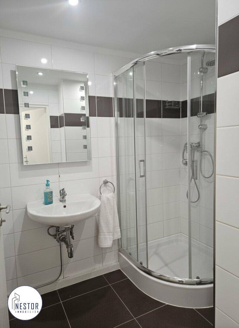 Modernes Badezimmer mit Duschkabine, Waschbecken und weißen Fliesen.