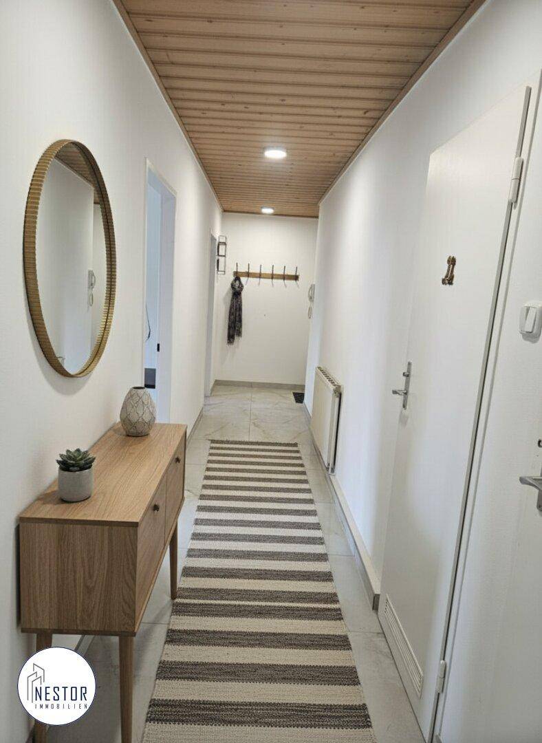 Heller Flur mit Holzdecke, Garderobe und modernem Sideboard.