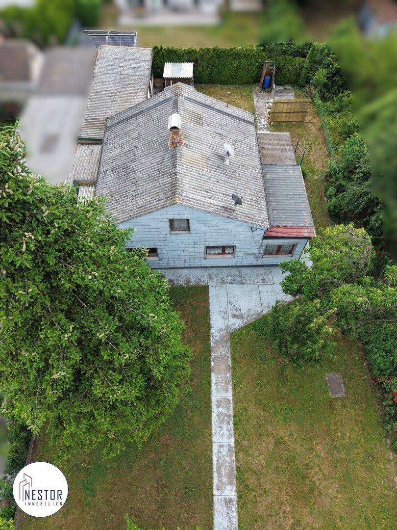 Detaillierte Luftaufnahme des Hauses von hinten mit gepflegtem Garten und Photovoltaikanlage auf dem Anbau.