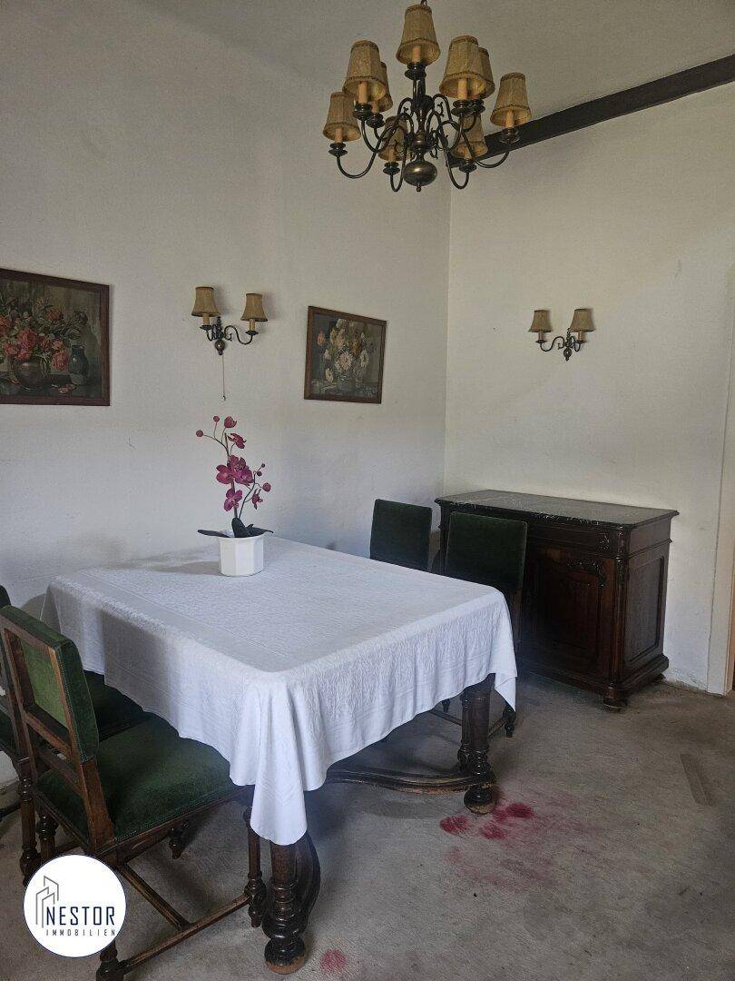 Esszimmer mit klassischem Holztisch, Stühlen und einem Kronleuchter, bereit für Mahlzeiten.