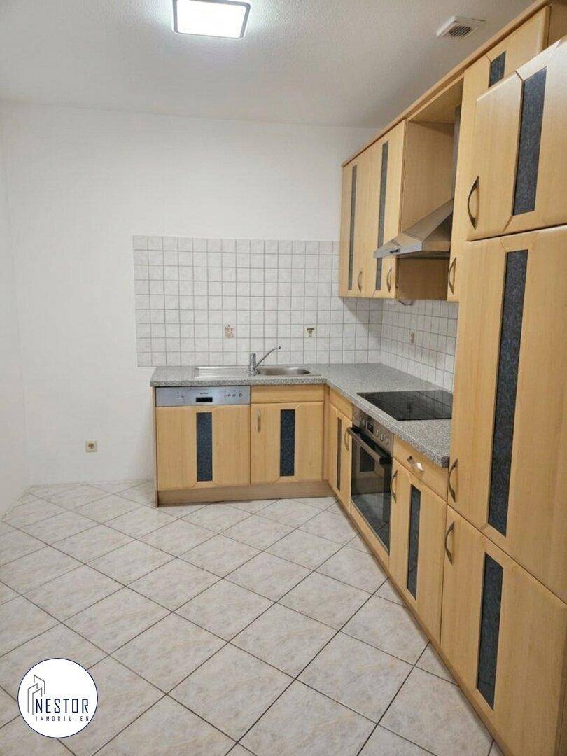 Einbauküche mit hellen Holzfronten, Fliesenboden und Spülmaschine, in gutem, gepflegtem Zustand.