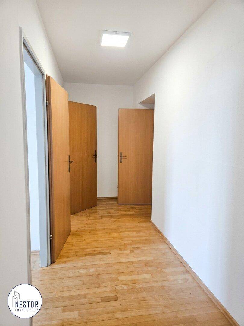 Geräumiger Flur mit hellem Parkettboden und mehreren Holztüren, die zu den angrenzenden Zimmern führen.