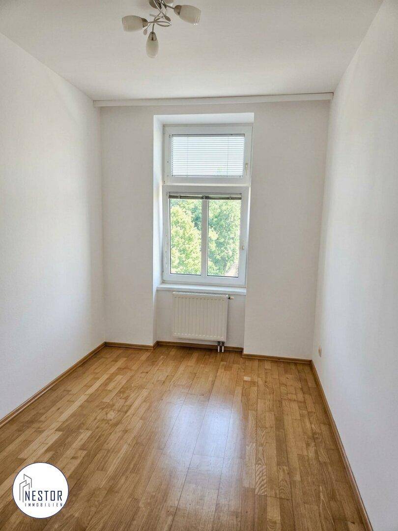 Kleiner, heller Raum mit Parkettboden und einem Fenster mit Blick ins Grüne, ideal als Kinderzimmer.