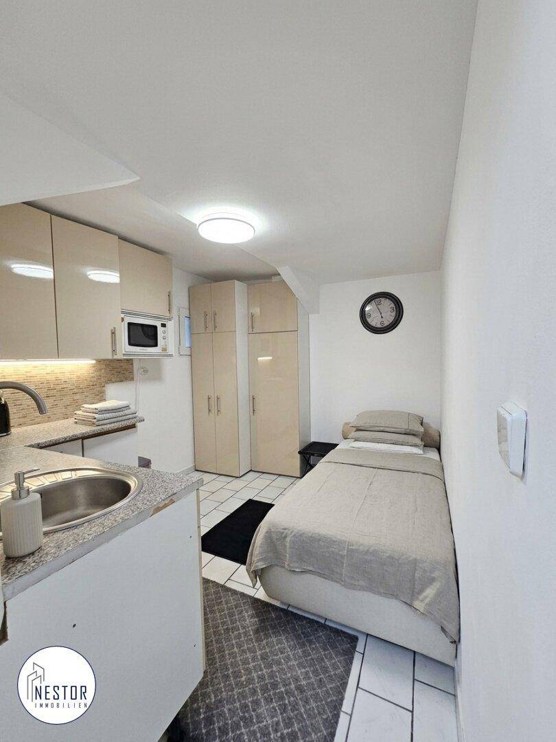 Kleines Zimmer mit Einzelbett und integrierter Küchenzeile, ideal für Gäste oder als Studio.