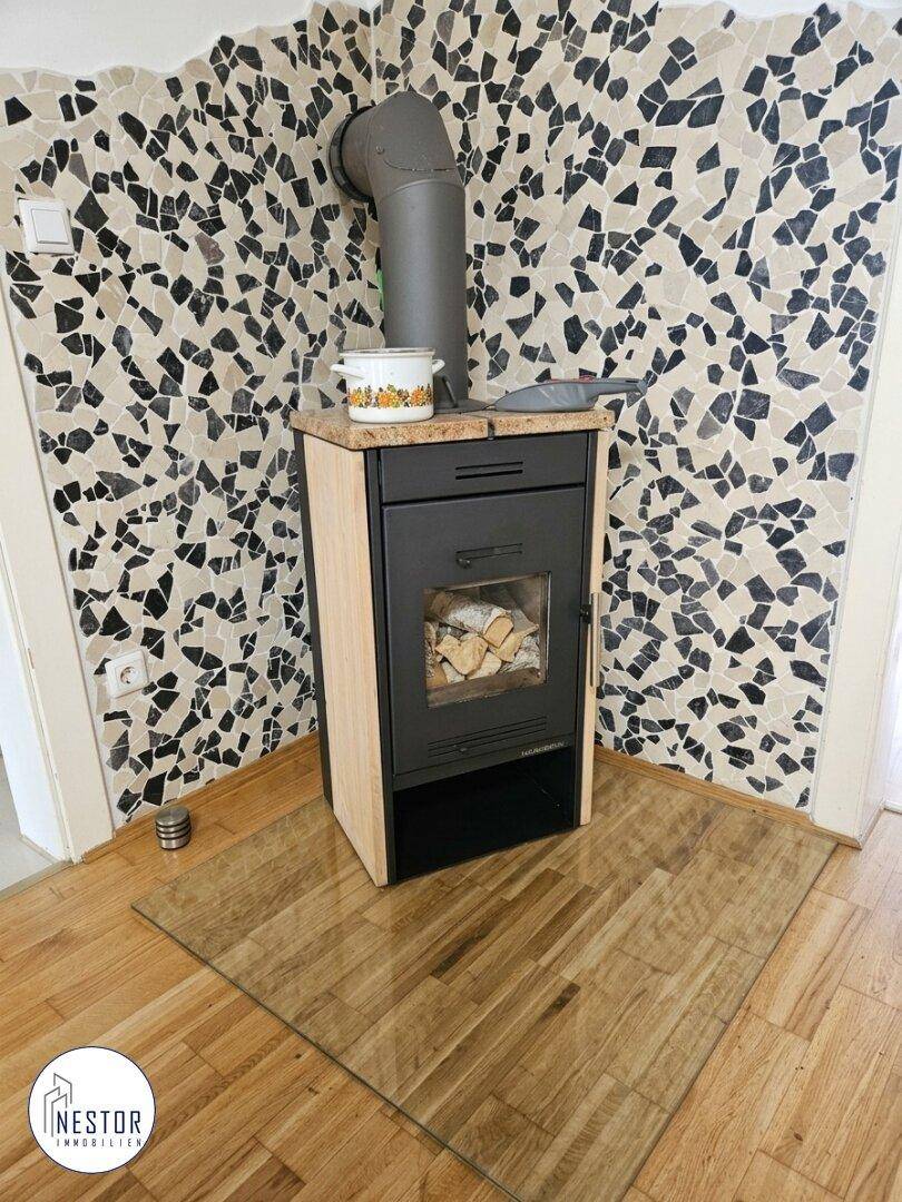 Gemütlicher Wohnbereich mit modernem Holzofen und dekorativer Wandverkleidung.