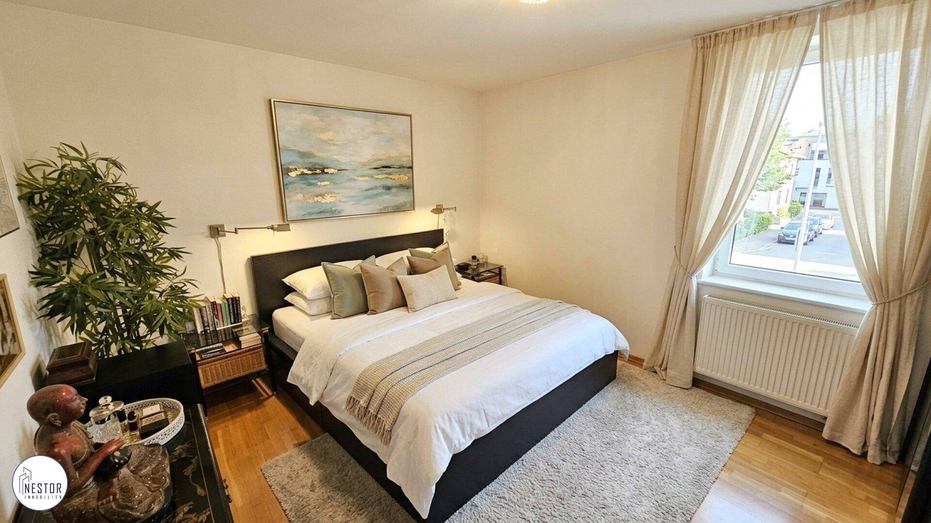 Helles Schlafzimmer mit Doppelbett, Holzboden und großem Fenster zur Straße.