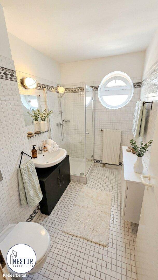 Modernes Badezimmer mit Dusche, Waschbecken und runden Fenstern.
