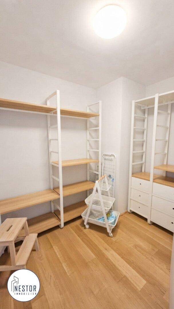 Praktischer Raum mit offenen Regalsystemen und Holzfußboden, ideal als Ankleide oder Abstellraum.