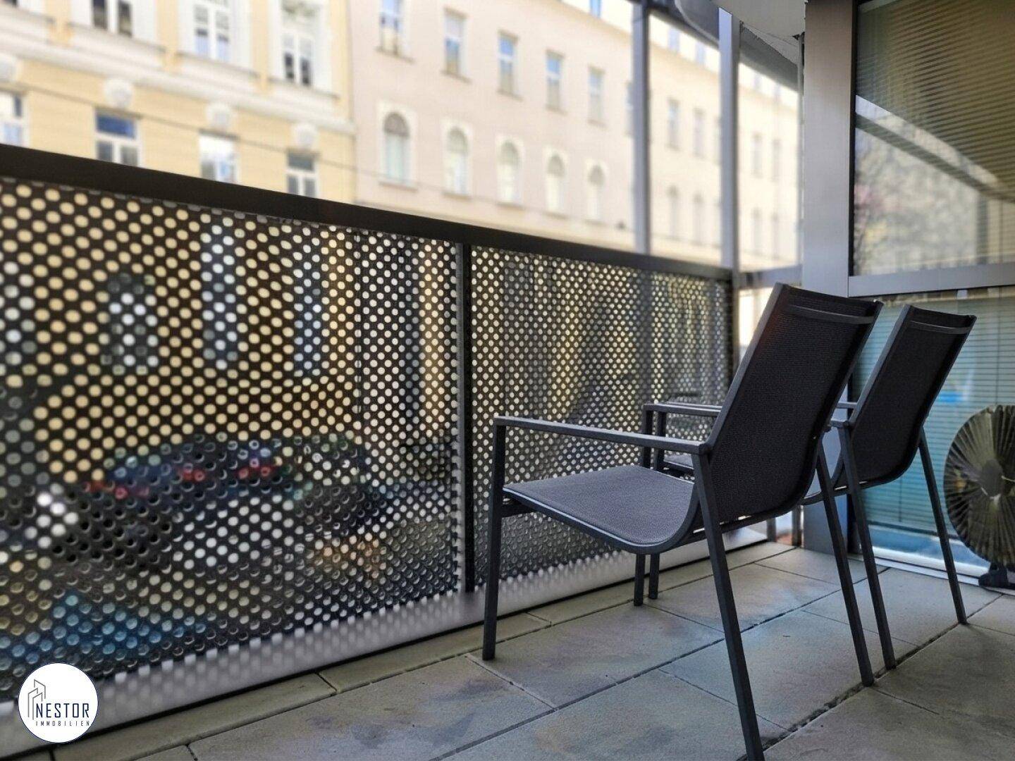 Gemütlicher Balkon mit Sitzgelegenheiten und moderner Lochblech-Brüstung, mit Blick auf die Stadt.