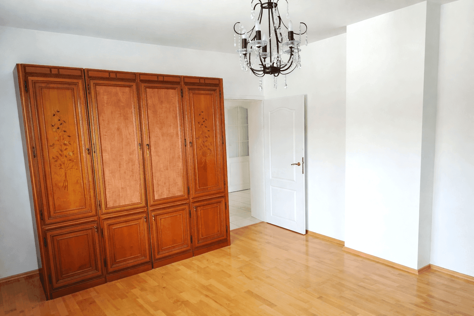 Helles Zimmer mit großem Holzschrank, Holzfußboden und Kronleuchter, vielseitig nutzbar.