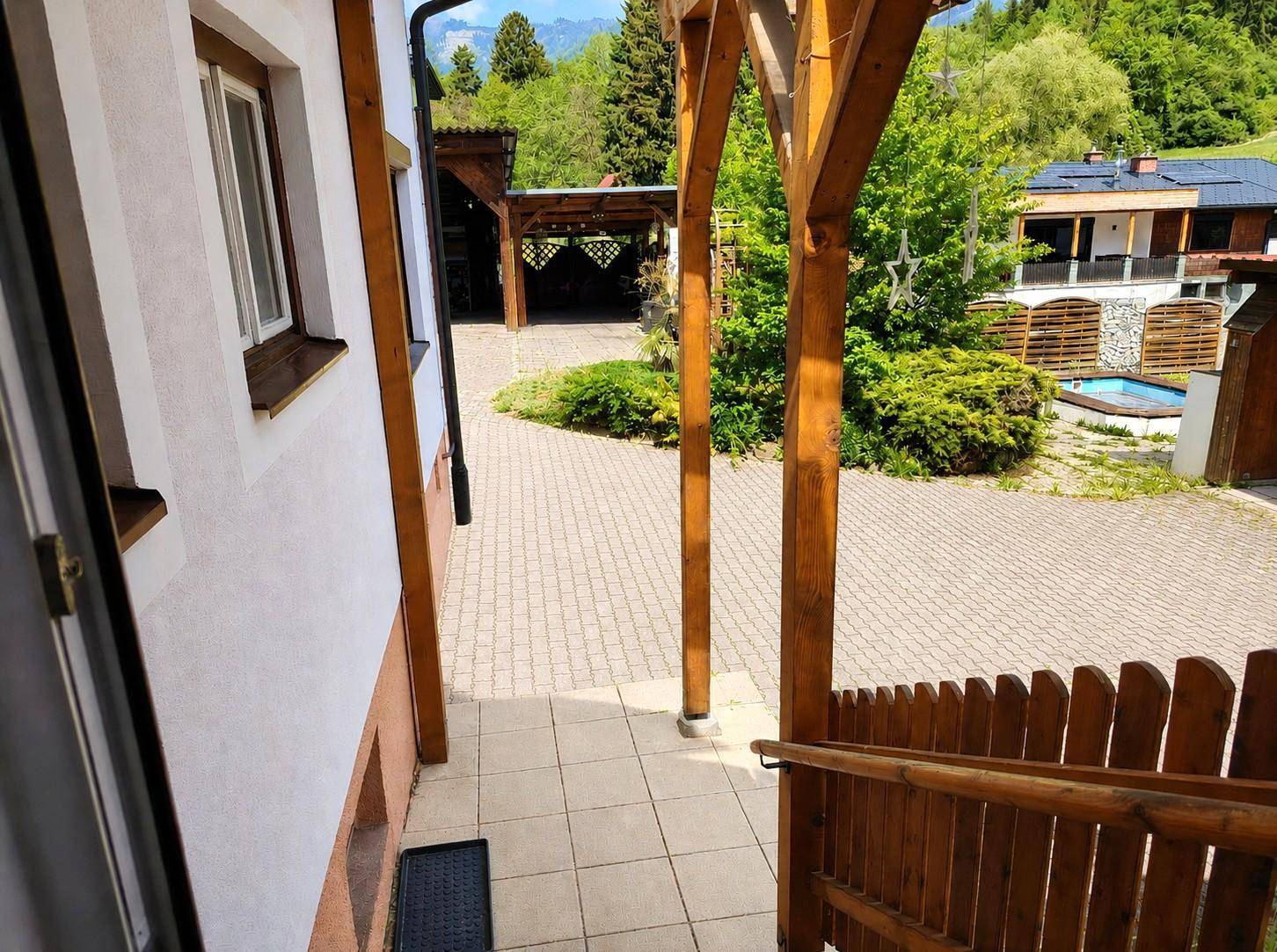Gepflasterter Hofbereich mit Holzstützen und Blick auf die umliegende Berglandschaft.