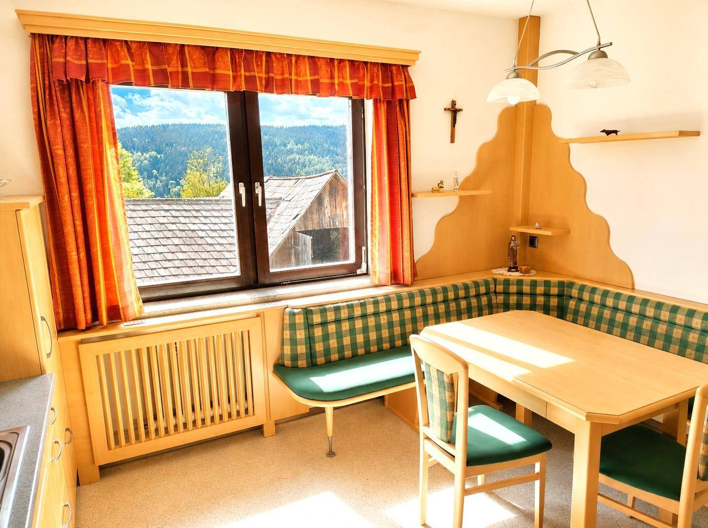Gemütliche Essküche mit Eckbank, Holzmöbeln und Blick auf die ländliche Umgebung.